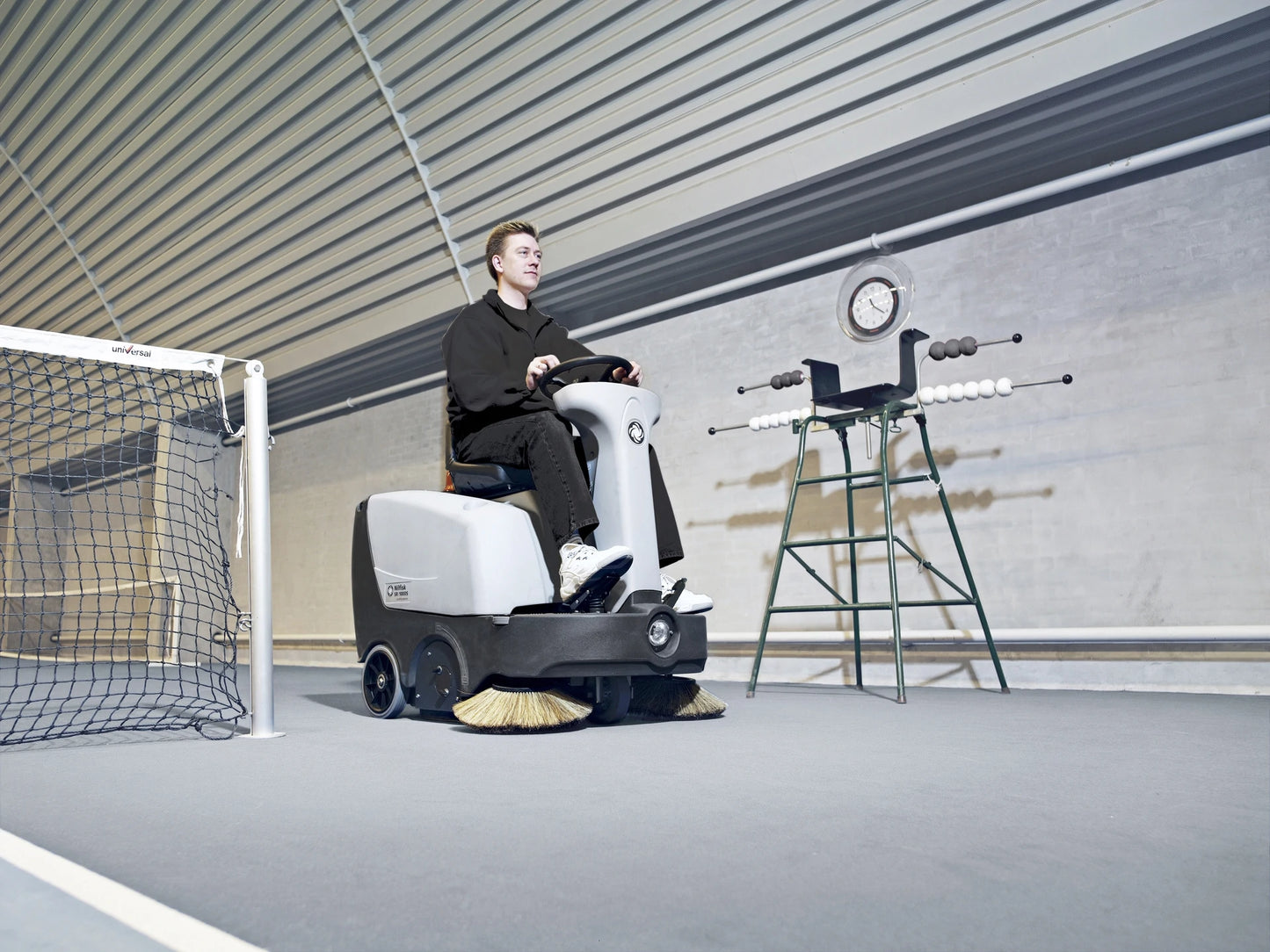 Ein Mann, der mit dem Nilfisk SR1000S in einer Tennishalle fährt