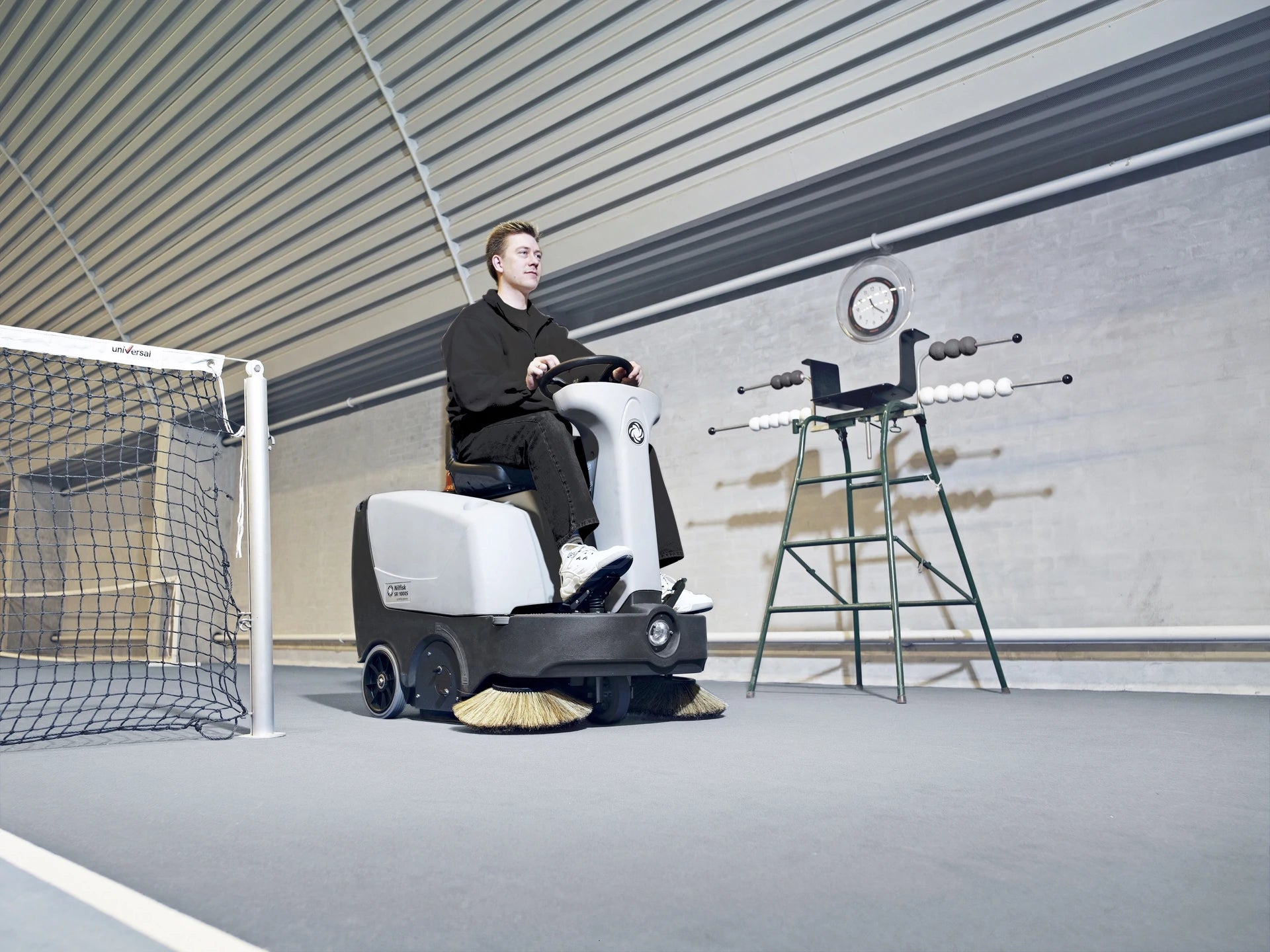 Ein Mann, der mit dem Nilfisk SR1000S in einer Tennishalle fährt